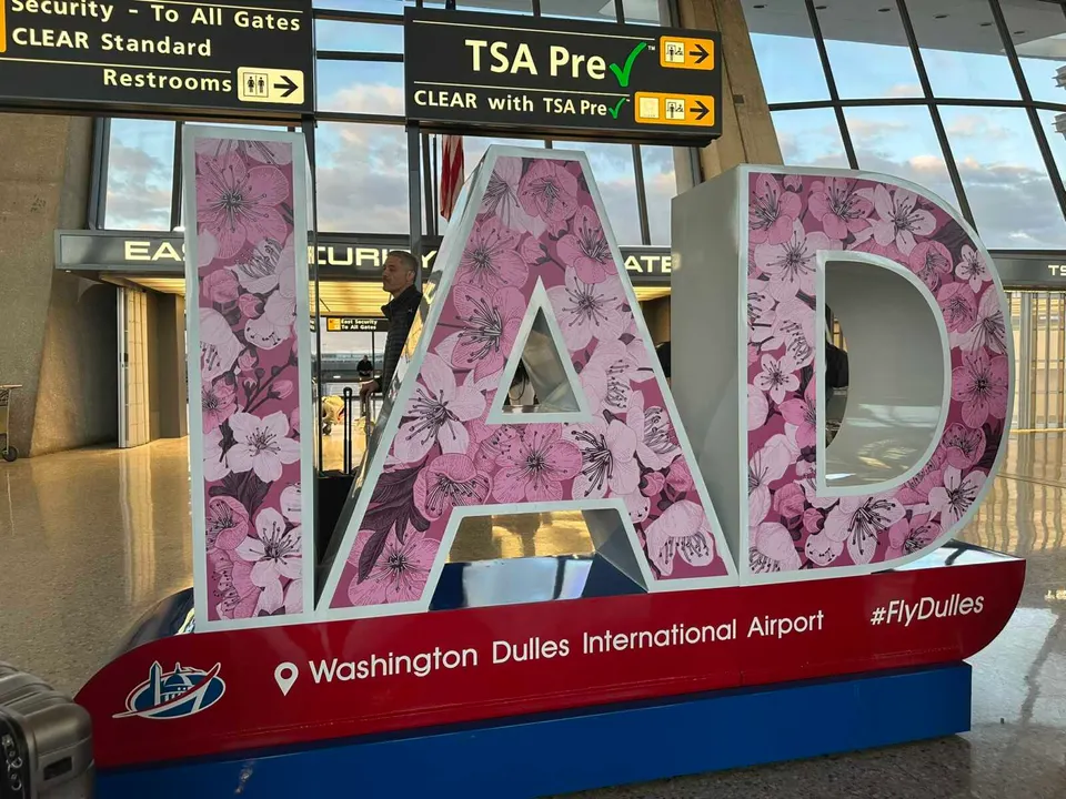 A cherry blossom-decorated sign welcomes travelers to Dulles International Airport (staff photo by Angela Woolsey)