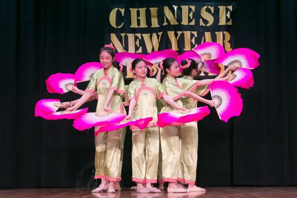 Lunar New Year dancers on stage in a circle with with pink fans