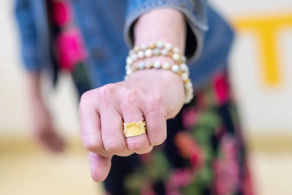 A woman's hand with a construction paper ring on.