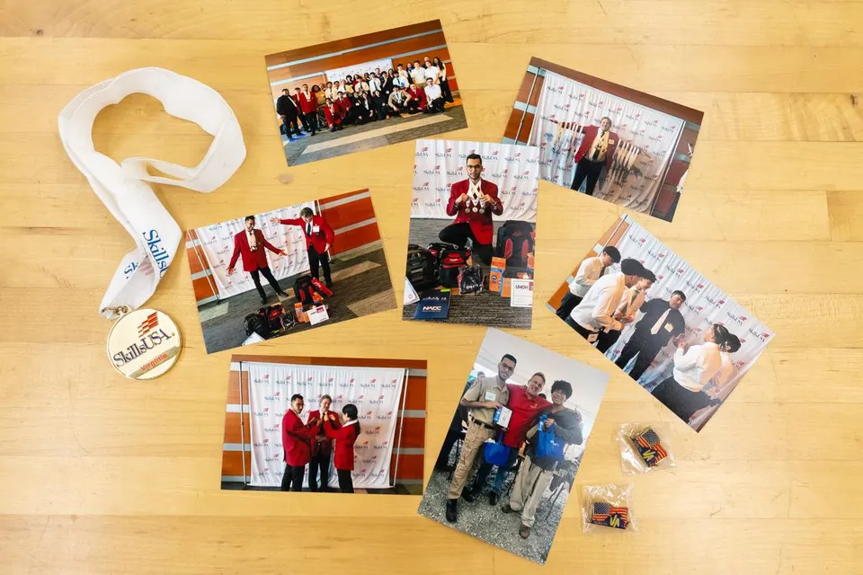 SkillsUSA medal, pins, and event photos displayed on a table.