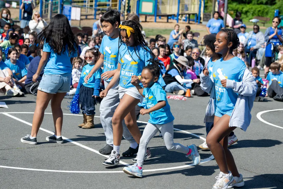 Students in blue shirts run across a blacktop.