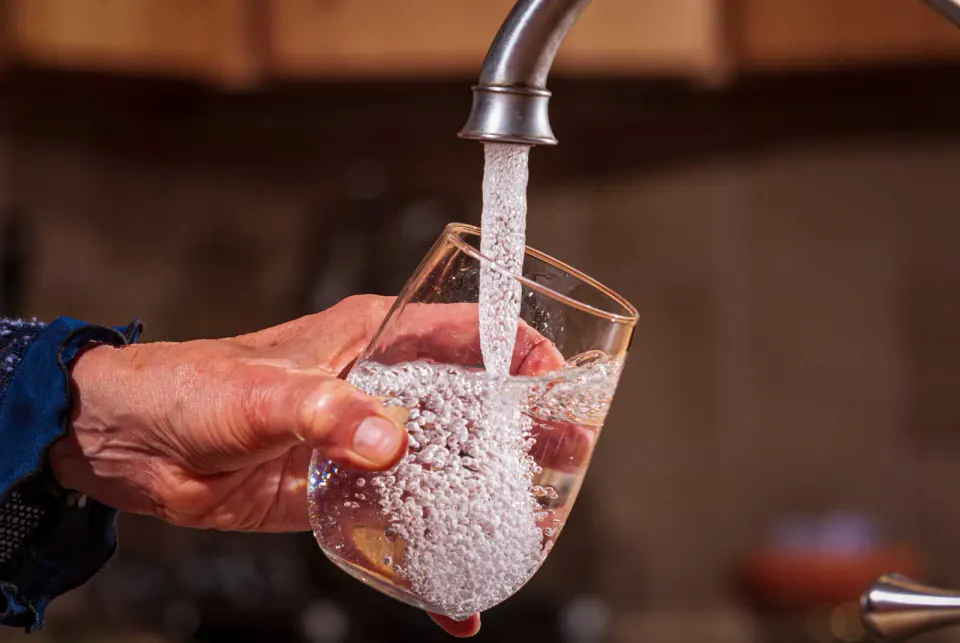 A person fills a glass with tap water (photo by Eric Vance/U.S. EPA)