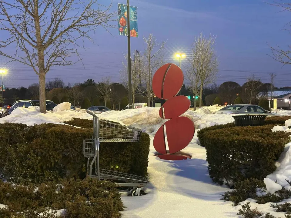 A shopping cart and Al Landzberg’s “Slit Figure” sculpture in snow at Plaza America in Reston (staff photo by Angela Woolsey)