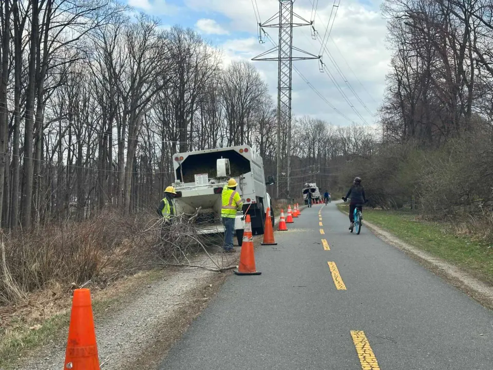 A bicyclist passes tree workers on the W&OD Trail in Vienna (staff photo by Angela Woolsey)