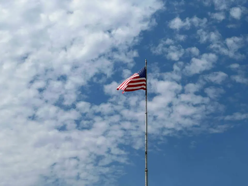 A U.S. flag against blue sky in Fairfax (staff photo by Angela Woolsey)