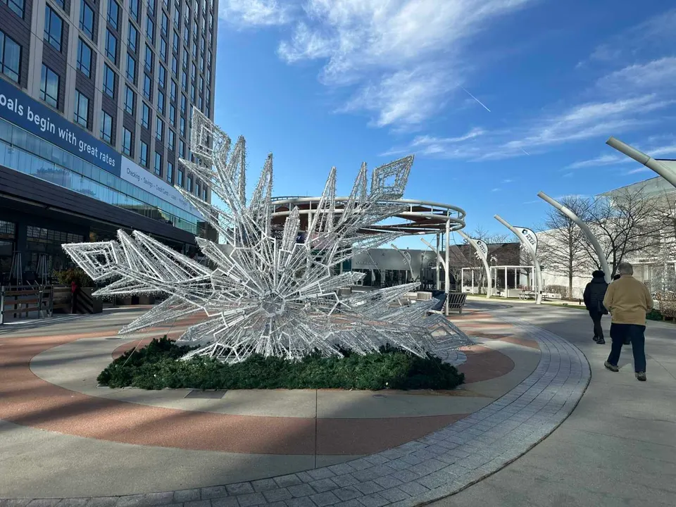 People walk past an Enchant Light Experience snowflake sculpture on PenFed Plaza at Tysons Corner Center (staff photo by Angela Woolsey)