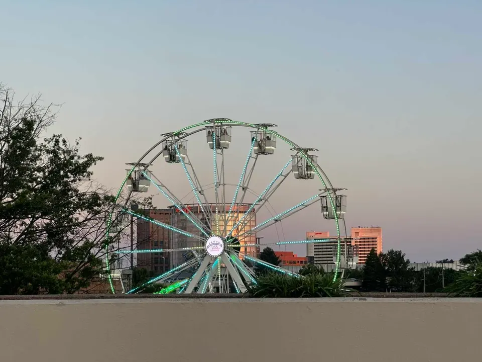 Ferris wheel for the Tysons Carnival turns with the Strategy headquarters building in the background (staff photo by Angela Woolsey)