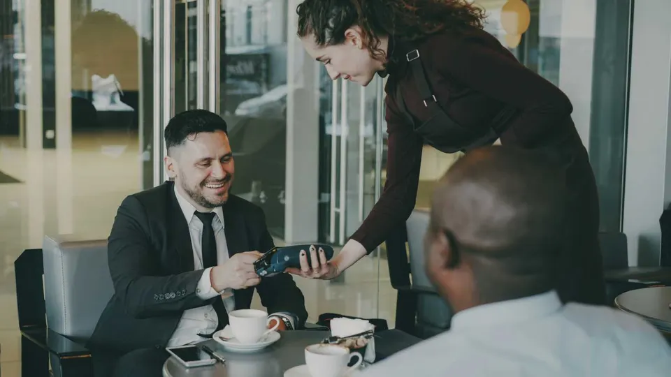 Man in business suit pays for drinks at a cafe (photo via Vitaly Gariev on Unsplash)