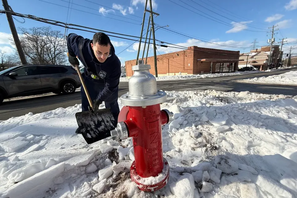 man shoveling snow by fire hydrant