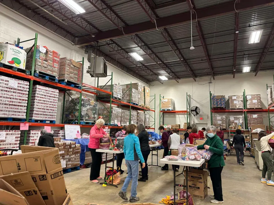 Volunteers pack donations that will go to schools at Food for Others’ Merrifield warehouse (staff photo by Angela Woolsey)