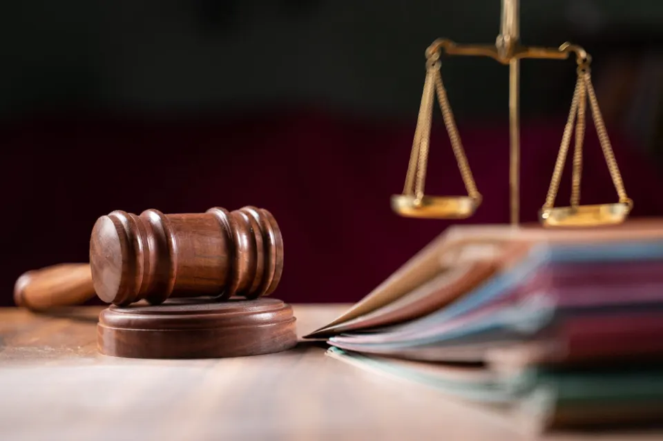 focus on hammer, group of files on judge table covered with dust – concept of pending old cases or work…