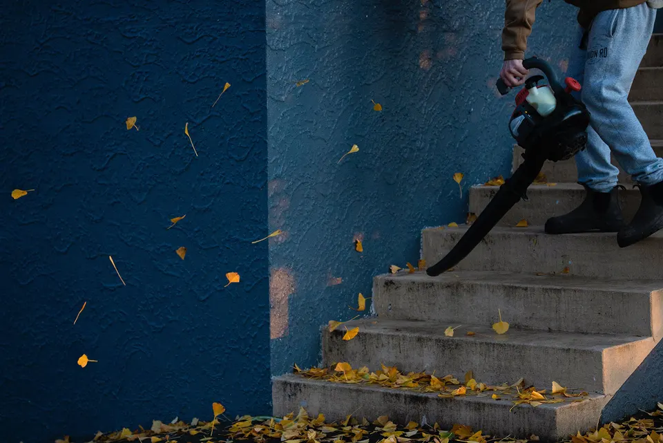 Person using a gas-powered leaf blower on stairs (via Callum Hill on Unsplash)