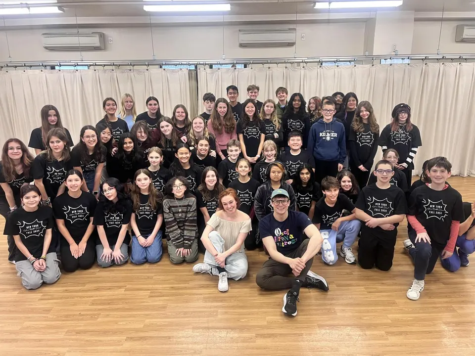 Large group of students and instructors pose together in a classroom after a theater workshop.