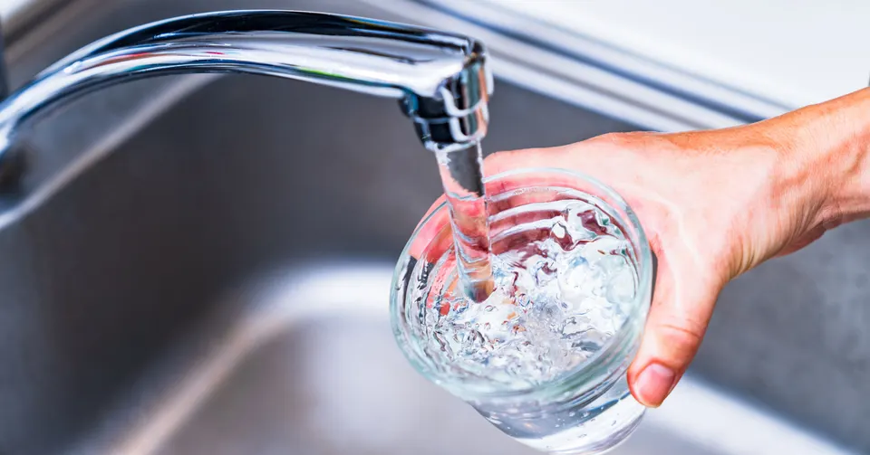 woman hand holding cup under running sink