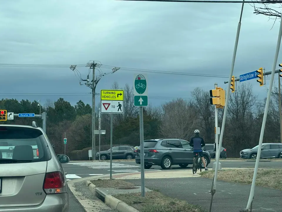 A bicyclist stopped at the intersection of Route 50 and Stringfellow Road in Chantilly (staff photo by Angela Woolsey)