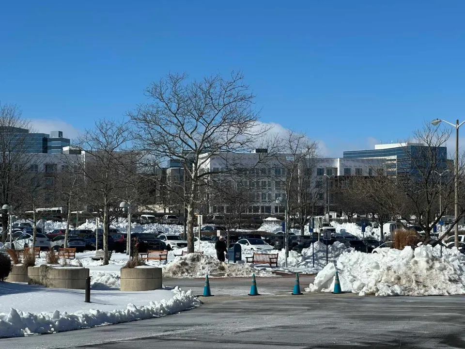 A person walks past benches in snow near the Fairfax County Government Center parking lot (staff photo by Angela Woolsey)