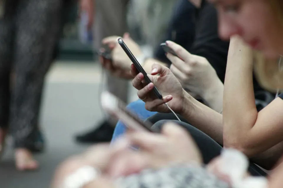 People looking at and scrolling on smartphones (via ROBIN WORRALL on Unsplash)