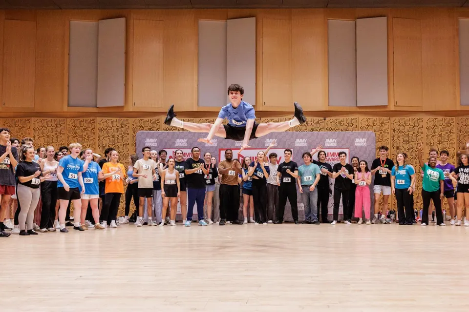 Student John Poncy takes a huge leap in the air with the cast stood behind him.