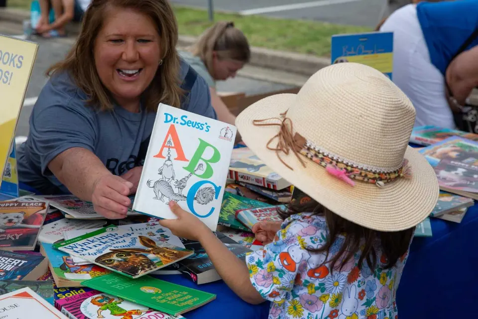 A kid picks up a Dr. Seuss book at Fairfax County’s 2025 Children’s Summer Reading Festival (photo by Mike Leonard, courtesy of Fairfax Library Foundation)