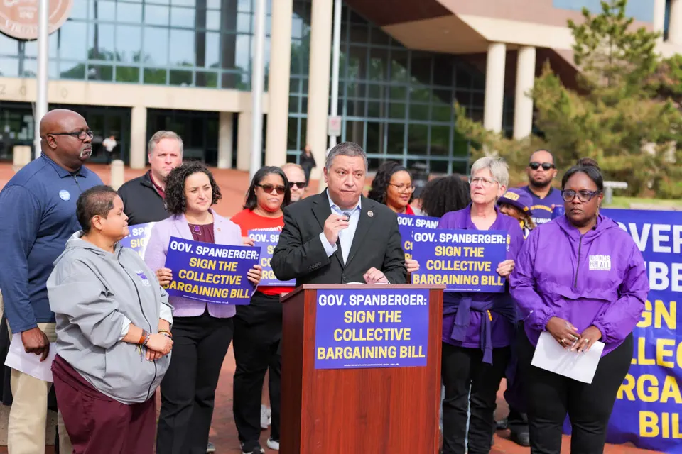 Workers and a county supervisor gather around a podium outside the Fairfax County government center