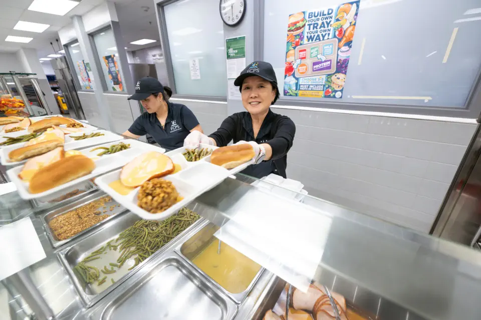 A food worker hands over a tray of thanksgiving-inspired food.