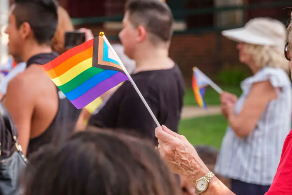 A community member waves an LGBTQ pride flag at the rally protesting Virginia’s model policies on transgender students (staff photo by Jay Westcott)