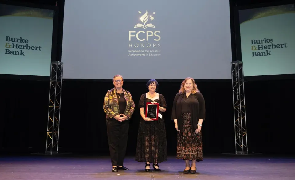 A woman holds an award on stage