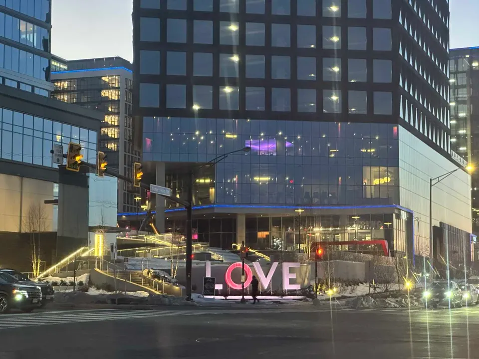 A person walks by the Love sign at the Wiehle Avenue and Sunset Hills Road intersection in Reston (staff photo by Angela Woolsey)