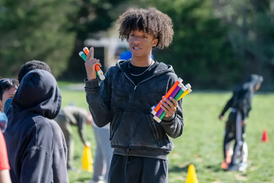 A high school track star coaches the younger children in the relay.