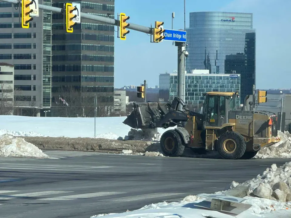 A front-end loader helps clear snowcrete from the intersection of Route 123 and International Drive in Tysons (staff photo by Angela Woolsey)