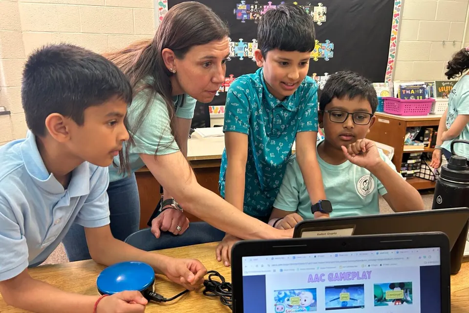 teacher and students huddled around screen learning