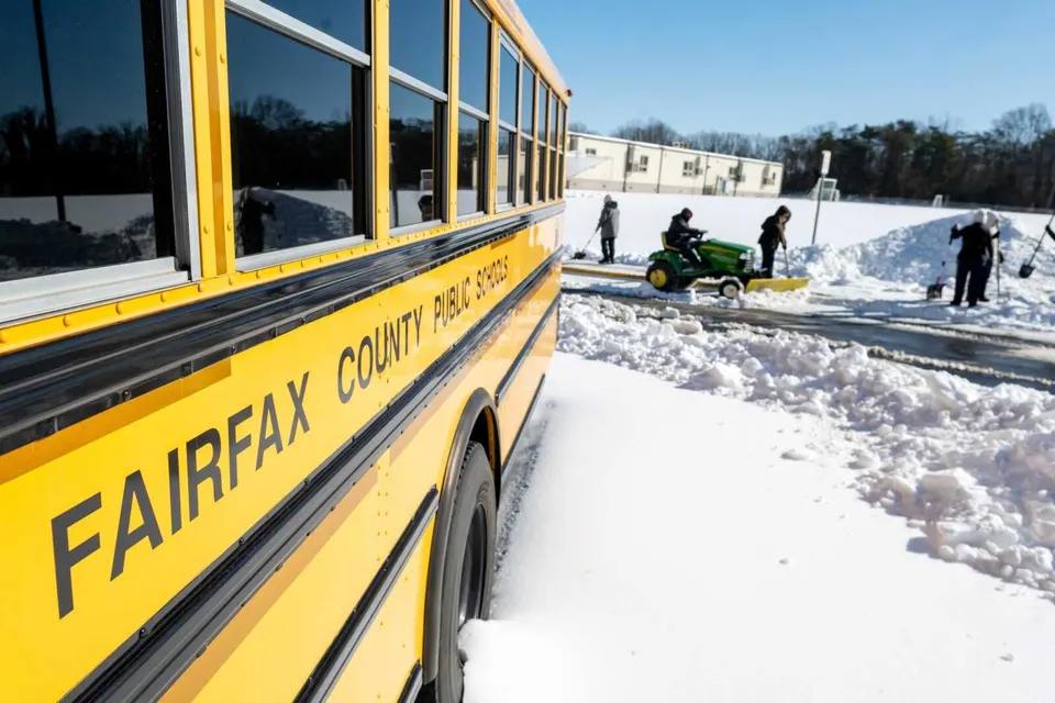 Fairfax County Public Schools workers clearing snow near a bus on Jan. 28, 2026 (via FCPS/Facebook)