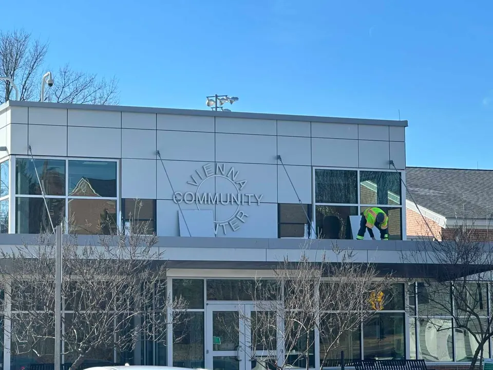 A worker on an awning over the Vienna Community Center entrance (staff photo by Angela Woolsey)