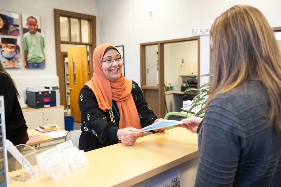 staff member smiles as she helps someone in the front office