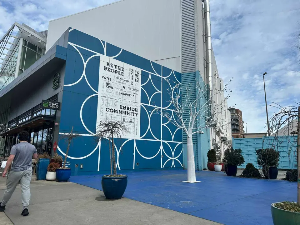 A white tree sculpture stands near a mural in the Mosaic District (staff photo by Angela Woolsey)