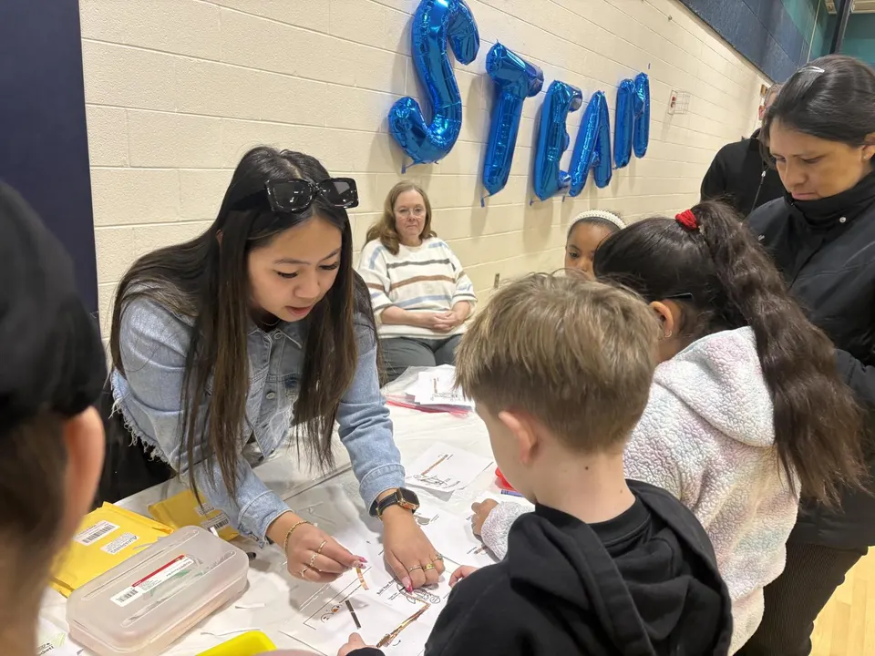 Students and an instructor work together on a hands-on STEAM activity at a school event.