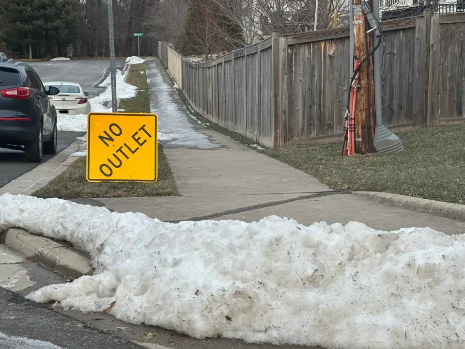 A “No Outlet” sign has fallen near a street curb in Vienna still blocked by snow (staff photo by Angela Woolsey)