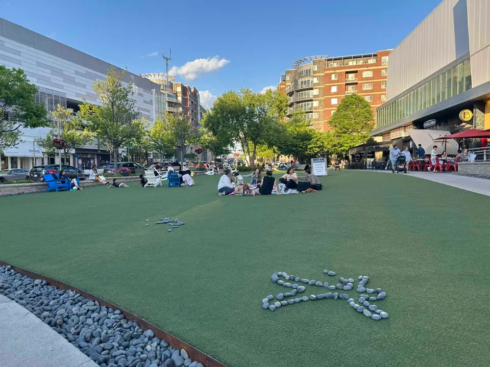 Rocks arranged in a person-shaped outline on the green at the Mosaic District in Merrifield (staff photo by Angela Woolsey)