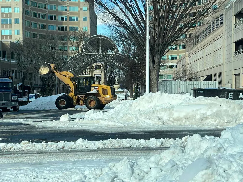 A bulldozer helps clear snow near the Reston Town Center pavilion after Winter Storm Fern (staff photo by Angela Woolsey)