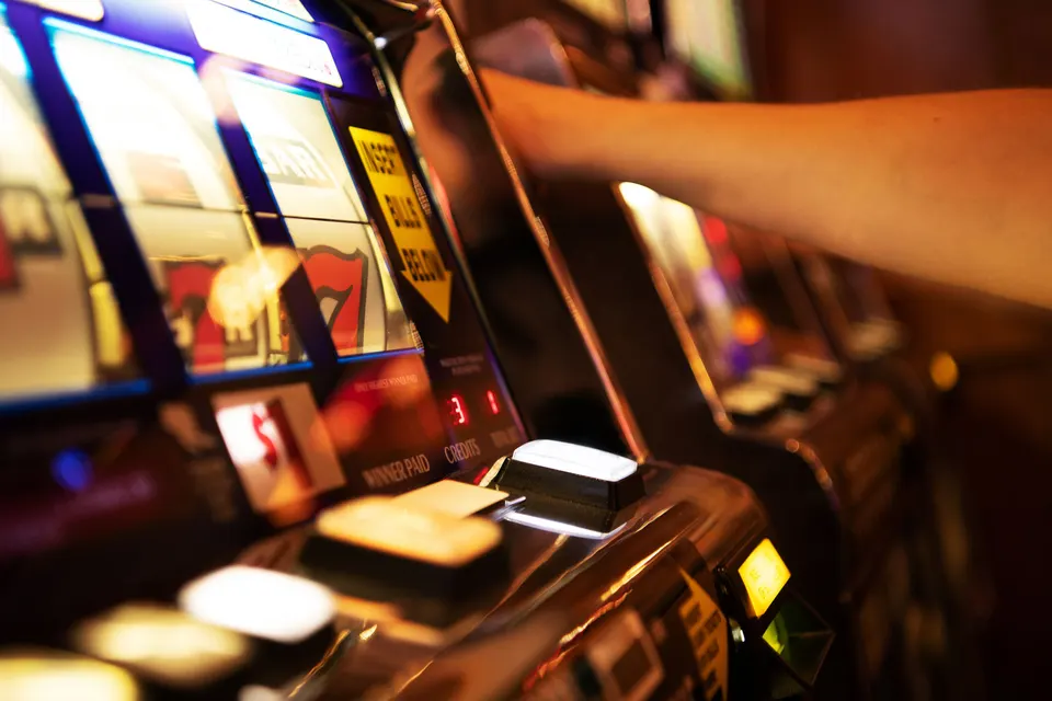 A player interacts with a slot machine in a lively casino, enjoying an exciting evening of gaming amid colorful lights and sounds.