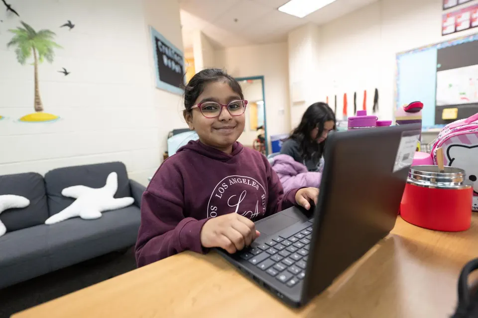 A child sits at a laptop in a classroom.