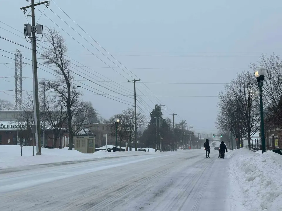 People in coats walk along Maple Avenue in Vienna during Winter Storm Fern on Jan. 25, 2026 (staff photo by Angela Woolsey)