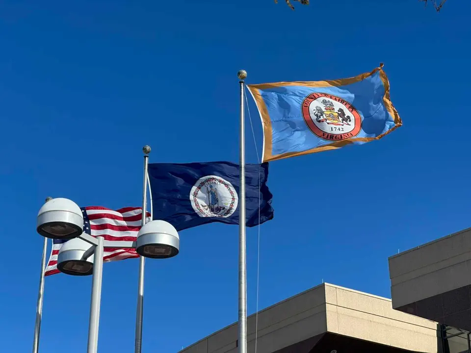 A Fairfax County flag flies next to Virginia and U.S. flags outside the Fairfax County Government Center (staff photo by Angela Woolsey)