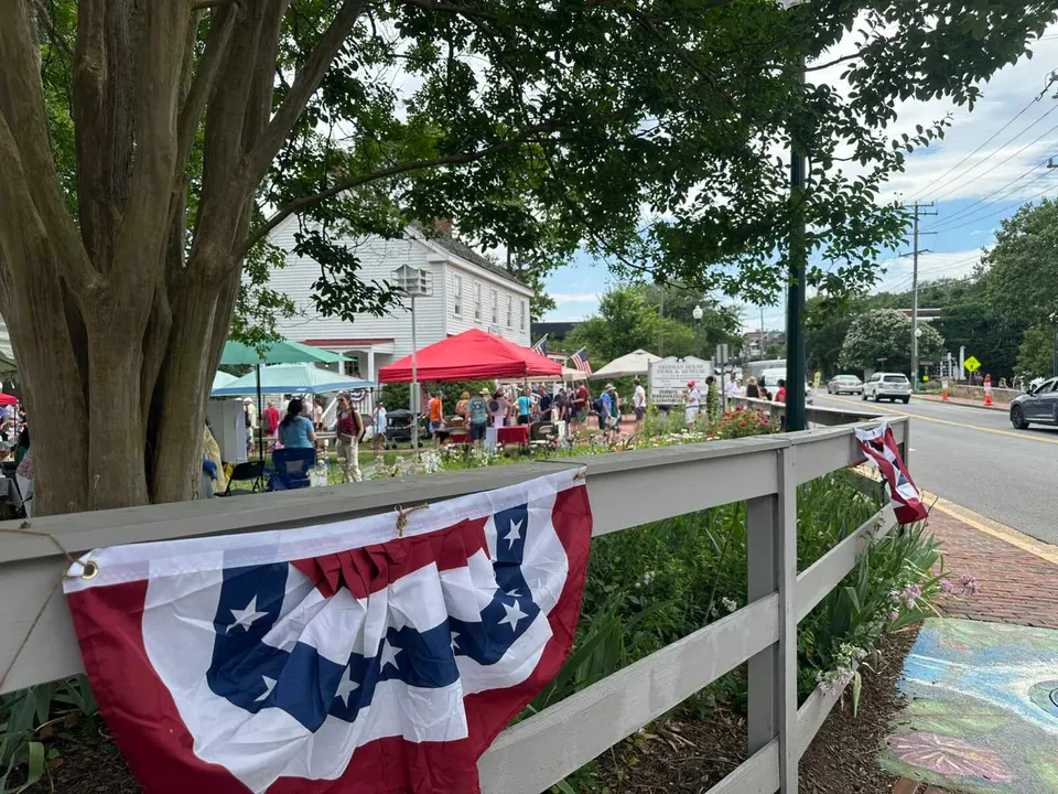A stars and stripes banner on a fence around the Vienna Town Green during a Flag Day celebration on June 14, 2026 (staff photo by Angela Woolsey)