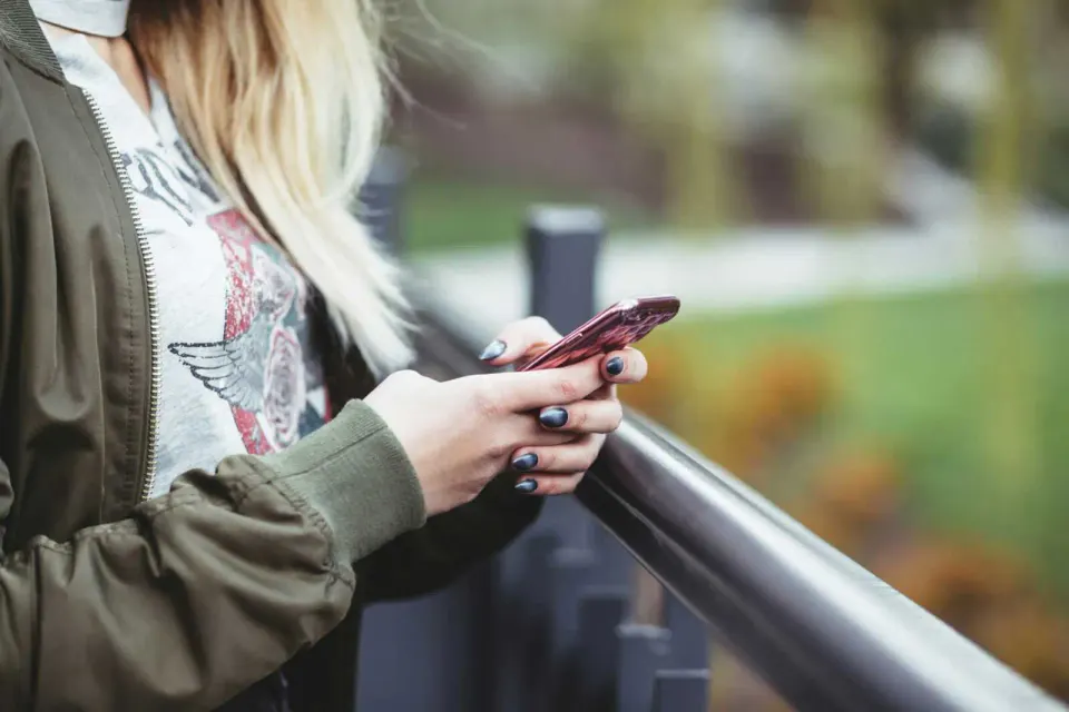 Woman types on smartphone (via freestocks/Unsplash)
