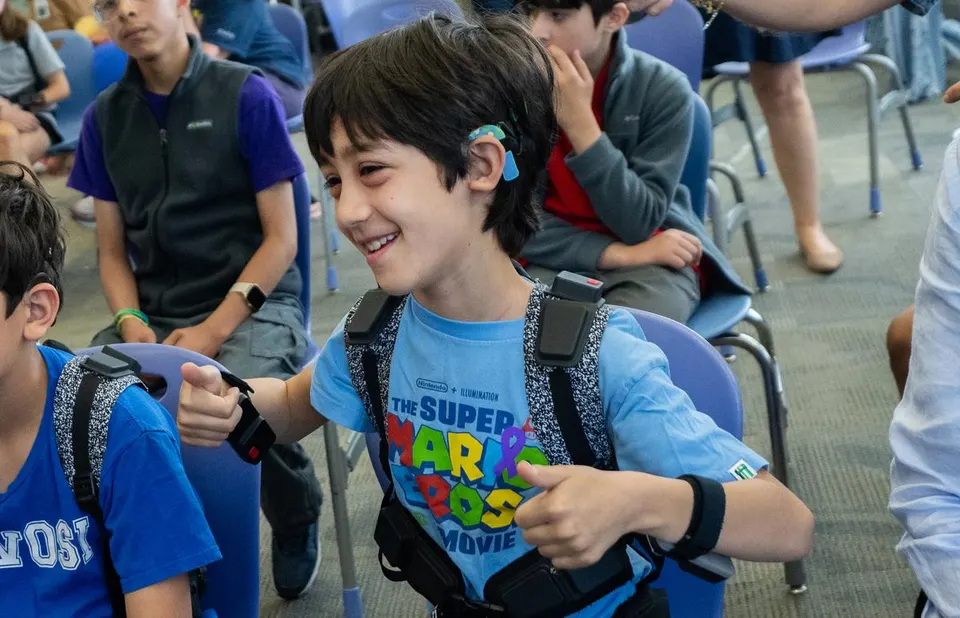 Student wearing adaptive technology smiles during an interactive classroom activity.
