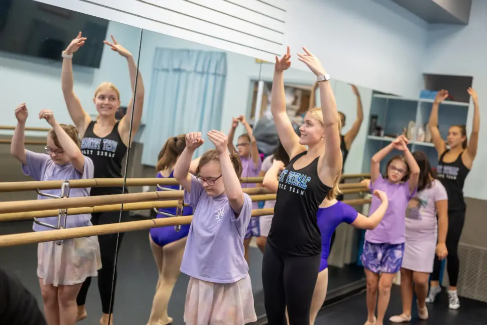 the dancers lead the younger girls at the barre
