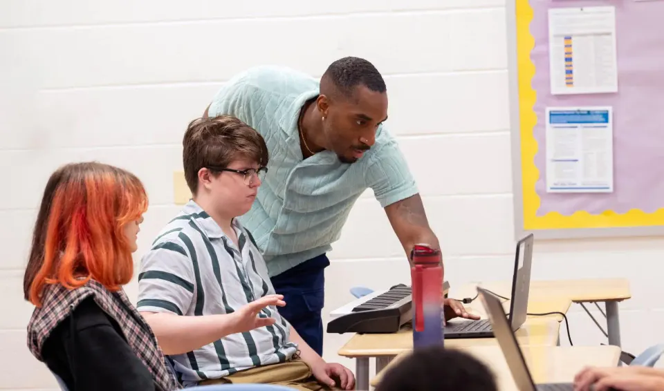 Luke looks at one of his student's laptops