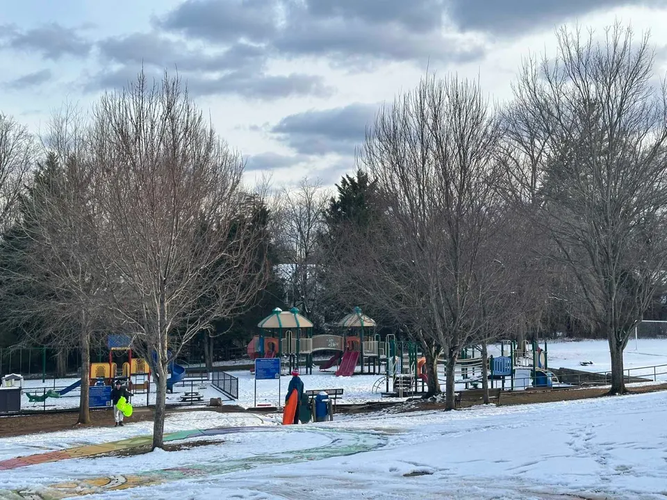 A couple people with sleds near the playground at Cunningham Park Elementary School in Vienna (staff photo by Angela Woolsey)