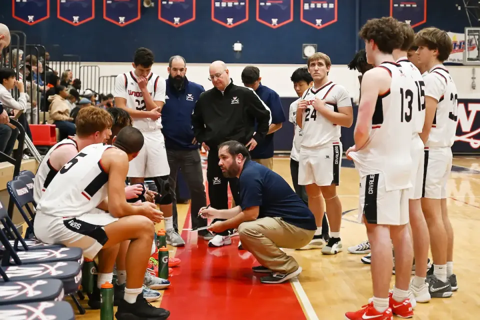 coach kneels to talk to his team during a time out
